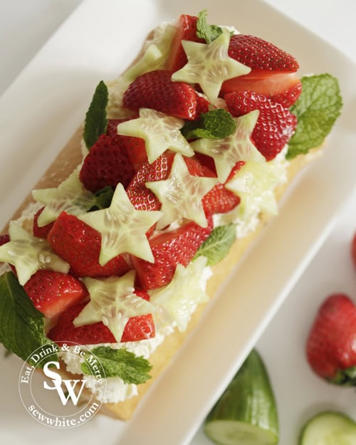 Pimm's Roulade Pimms Cake topped with star shaped cucumber slices, fresh strawberries find and whipped double cream