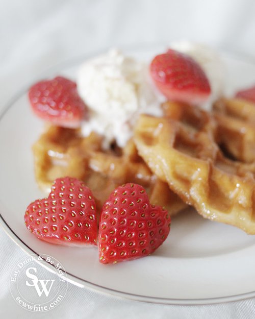 heart shaped strawberries served on a plate of hot doughnut waffles