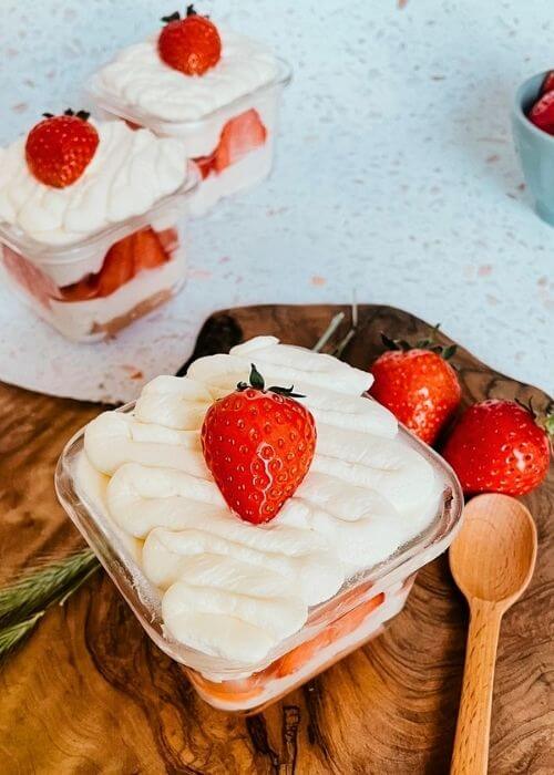 5 ingredients Mini Strawberry Cake Pots 4 from 45 angle - mini strawberry cake pots with strawberries around, on a wooden board, speckled background