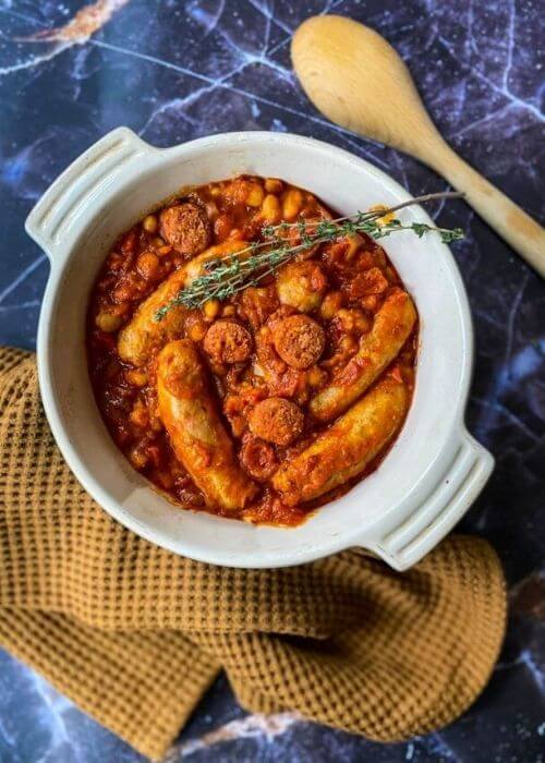 sausage and chorizo casserole with a napkin and spoon on the side, on a blue background