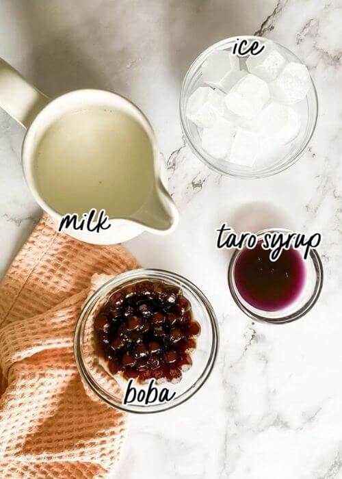Taro Latte Recipe: A Quick & Delicious Summer Drink 2 taro latte ingredients in bowls and jus, on marble background with a quilted towel