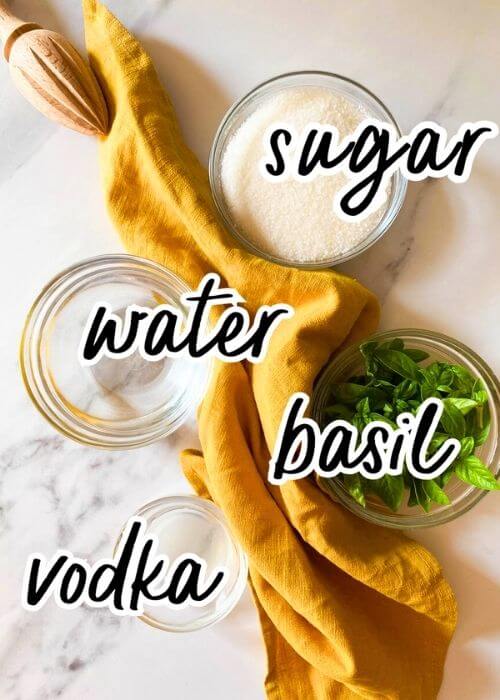 Easy Basil Lemon Martini - Delicious 10 Minutes Vodka Drink 2 ingredients for basil lemon martini in bowls on a marbled background with a yellow towel and lemon squeezer