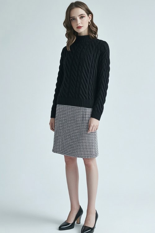 A woman wearing a black cashmere sweater paired with a houndstooth skirt and heeled loafers