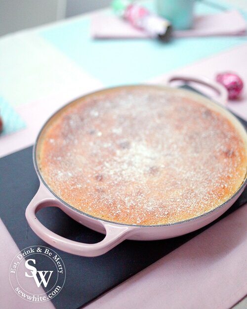 A golden brown summer fruit sponge pudding ready to be served in a chiffon pink Le Creuset shallow casserole dish. 