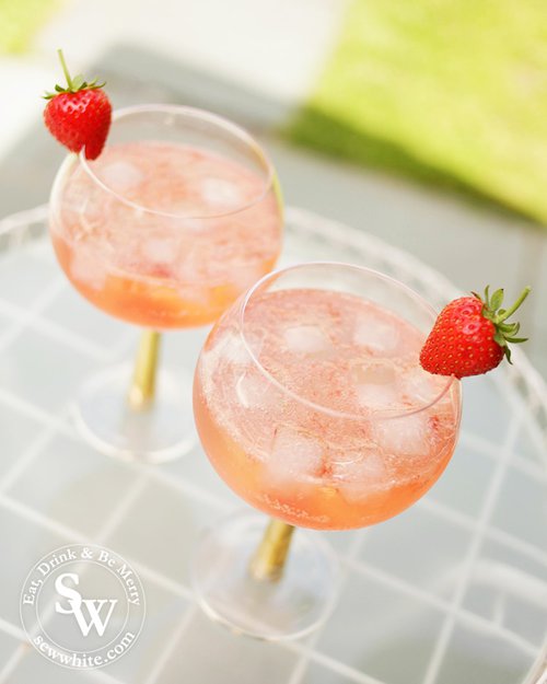 Golden red and orange gin and tonic balloon glasses with the Strawberry Jam Gin and Tonic. Decorated with a strawberry as decoration.