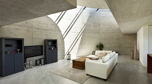 Modern industrial living room with concrete walls and minimalist furnishings.