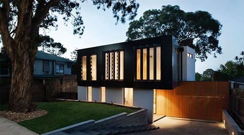 Sleek modern residential home by Bittoni Architects with black exterior and warm interior lighting.