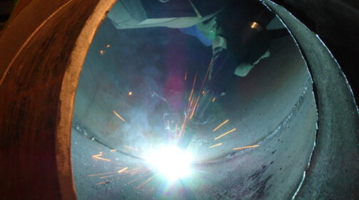 Operario ejecutando una soldadura industrial MIG MAG de alta penetración en un taller de fabricación metálica en España.