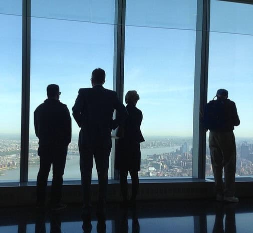Business professionals overlooking city skyline from office window in a corporate setting.