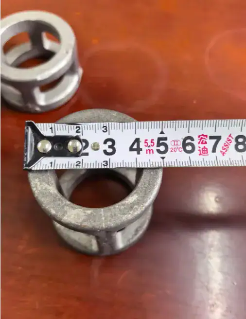 Slotted metal spacer sleeves beside a tape measure