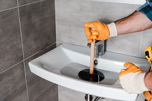 Plumber in Coplay PA Man from Coplay PA Plunging a Clogged Sink To Avoid Hiring Plumber