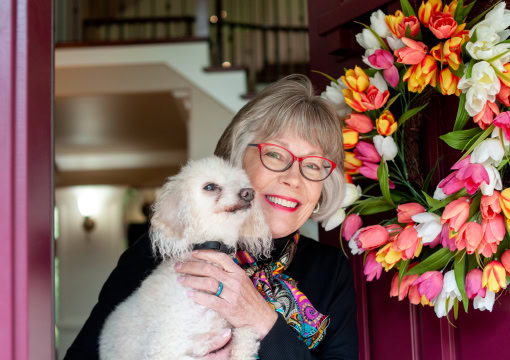 Sharon opening front door of home holding her dog