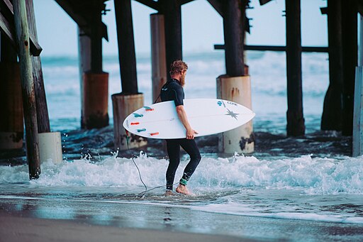 A view of a surfer in Cocoa Beach, Florida, featuring golden sandy shores, rolling ocean waves, and a laid-back beach town atmosphere near top Cocoa Beach Florida beachfront hotels, where surfing is a favorite among the space coast attractions.