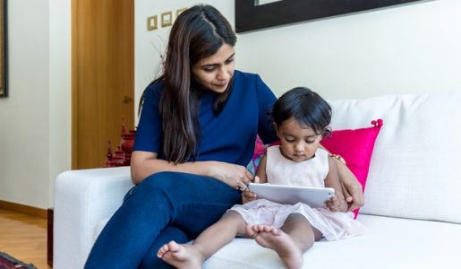 Little girl reading e book on tablet with her mother