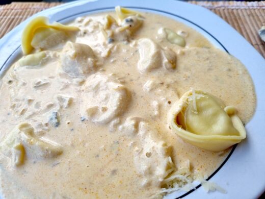 Mit Käse gefüllte Tortelloni. Mit Blau- und Schmelzkäsesoße und geriebenen Käse