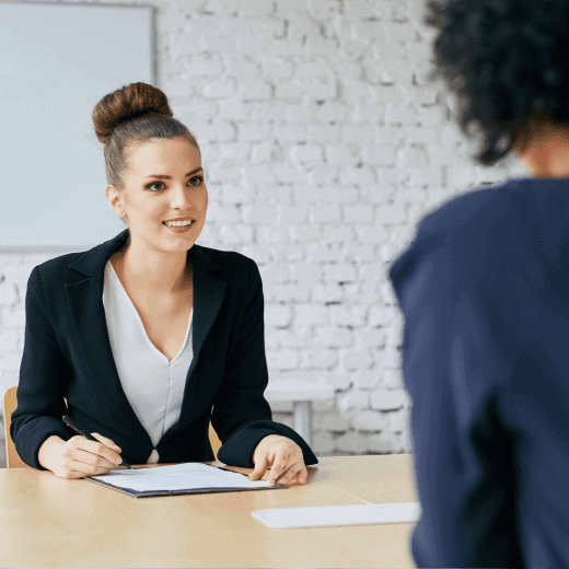 Two women sitting in a meeting room table discussing a paper.