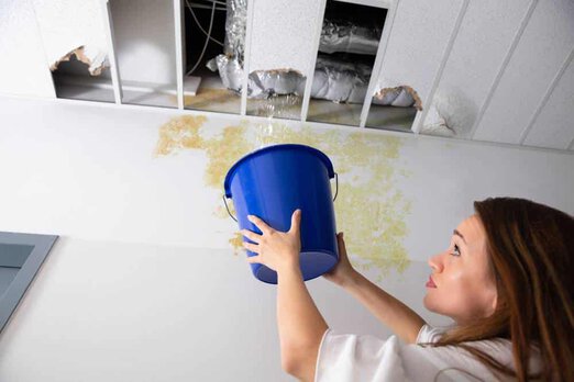 Woman catching ceiling leak