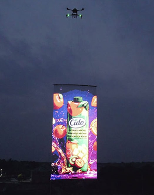 Drone flying LED screen displaying vibrant Cido juice advertisement in the night sky