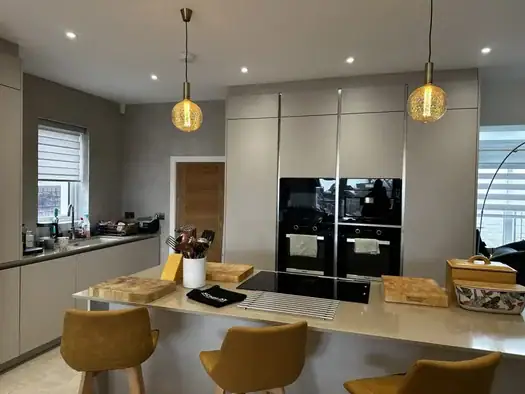 Modern beige kitchen with island and fitted appliances by Schmidt Swansea