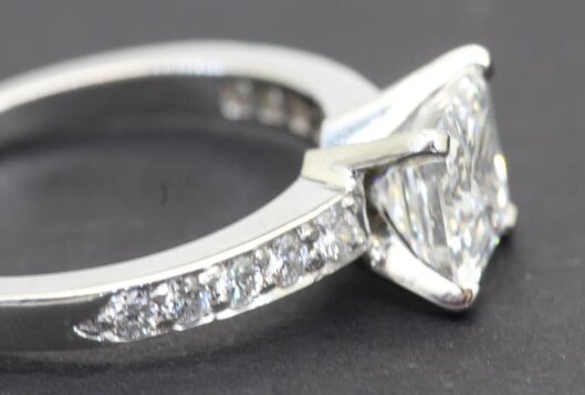 Silver engagement ring with sparkling diamonds on band and center stone.