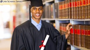 A young man in a graduation gown proudly holds his diploma, symbolizing achievement and future legal aspirations.