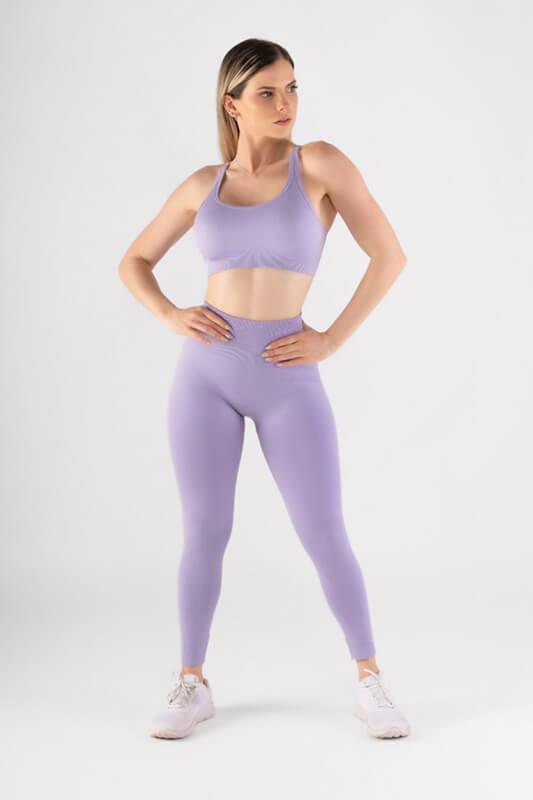 mujer de frente con sus manos en la cintura luce sujetador y leggins deportivo color lila