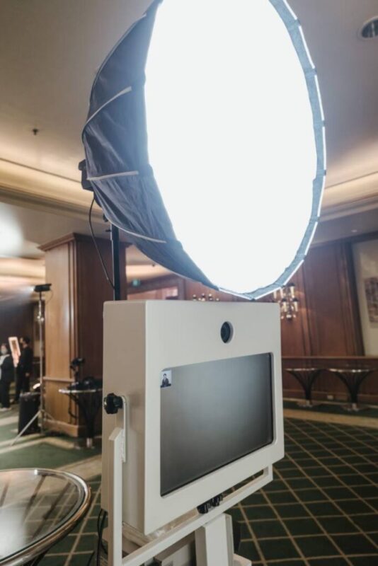 Studio photo booth camera kiosk lit by a large white parabolic softbox