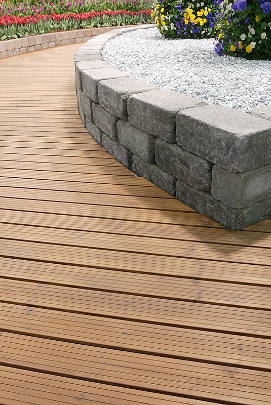 Bordázott felületű Thermowood teraszdeszka kőfal mellett
