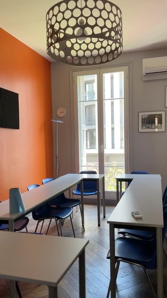 Moderner Klassenraum mit hellen Wänden, großen Fenstern und stilvoller Beleuchtung in einer Sprachschule.