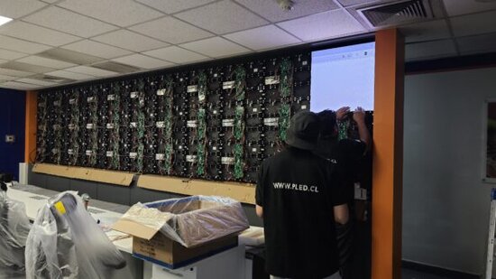 Técnicos de PLED realizando montaje y conexión de pantalla LED en sala de monitoreo 24/7 de Agrosuper