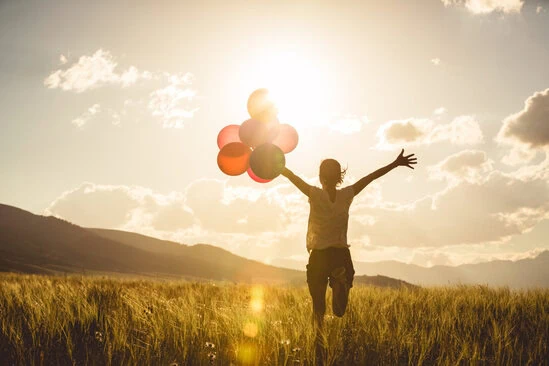 Cheering,Young,Asian,Woman,On,Grassland,With,Colored,Balloons
