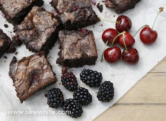 black forest brownies on greaseproof paper with fresh cherries and blackberries. 