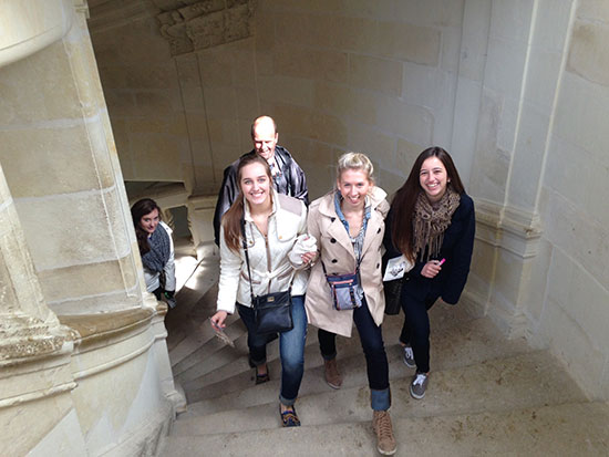 Students smiling at the camera as they climb steps