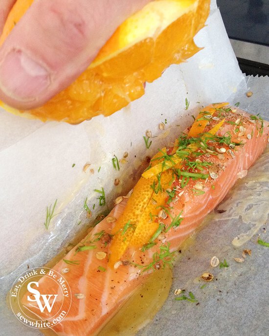 close up of the orange juice being squeezed over the salmon piece