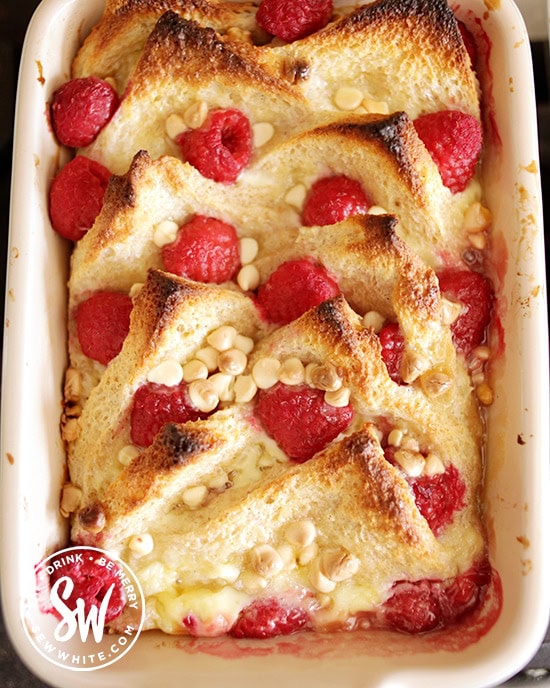 Top view of the golden brown Raspberry Bread and Butter Pudding with added white chocolate chips fresh from the oven. 