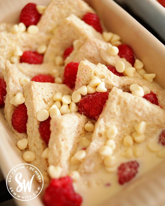 bread soaking in custard with pink raspberries and white chocolate chips