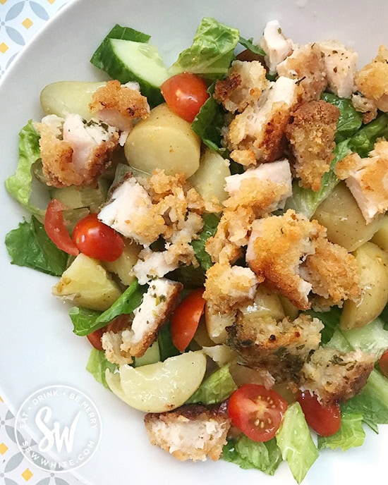 chopped up chicken kiev with boiled new potatoes, chopped up lettuce and baby tomatoes mixed together in a healthy salad.