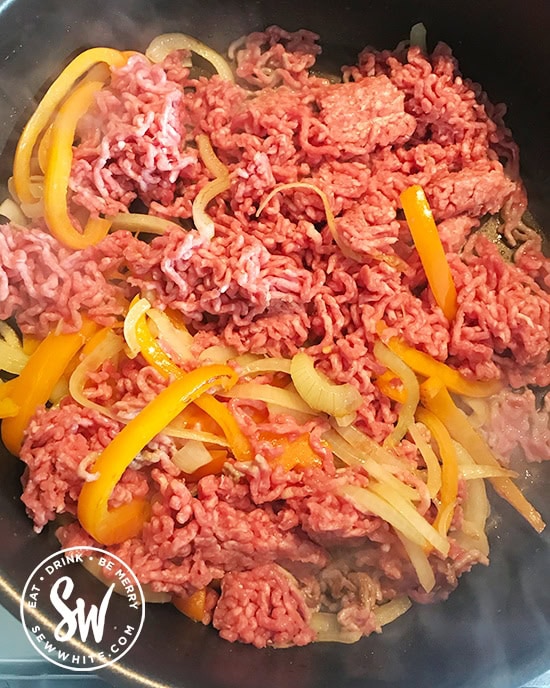 Stirring in the beef mince into the onions and peppers.