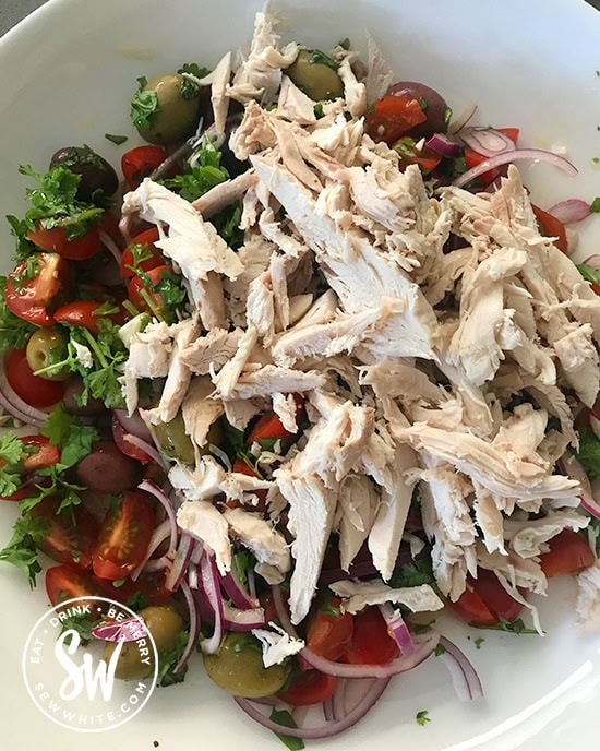 Mixing in leftover chicken shreds in to a salad with fresh herbs and vegetables. 