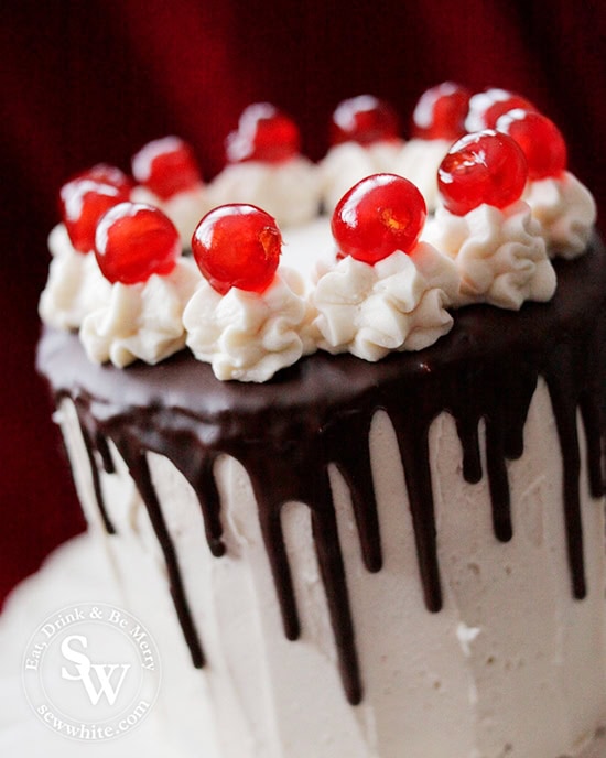 Easy black forest layer cake with dark chocolate trip and butter cream swirls topped with bright glace cherries