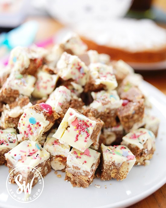 A mountain of bite size Maltesers Traybake cut up with sprinkles and jelly beans showing in the chocolate. 