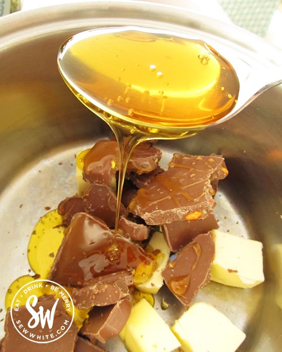 butter, chocolate and golden syrup being spooned in to a saucepan 