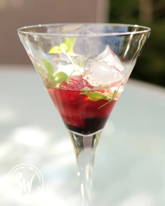 cocktail glass with mint, raspberries and ice cubes