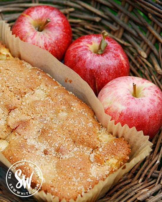 rosy red apples next to the freshly baked apple ginger loaf cake