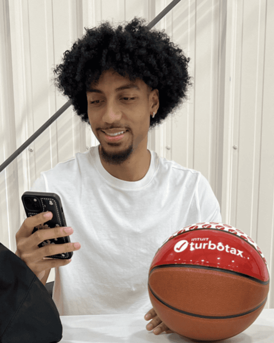 student ambassador posing with turbotax branded basketball, holding his phone