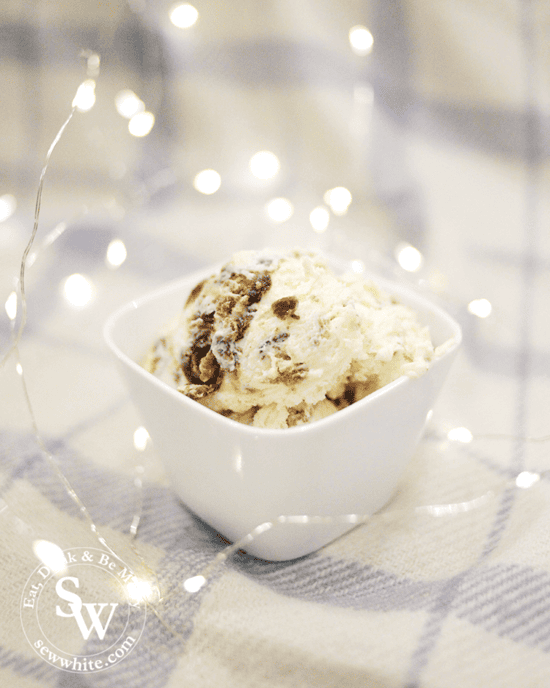 Easy Christmas Pudding Ice Cream using leftover christmas pudding. Scoops of the no churn ice cream in a bowl surrounded by fairy lights.