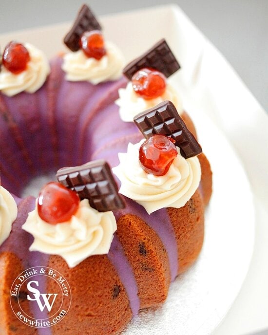 A close up of the glowing red cherries on top of the Black Forest Cake with purple glaze and mini chocolate bars