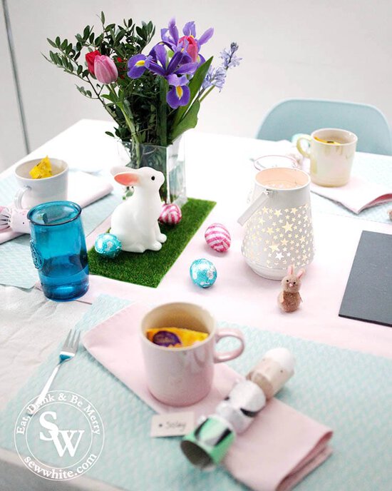 Easter Table Inspiration with pastel pink, blue and purples. Fresh flowers and little rabbits on fake grass.