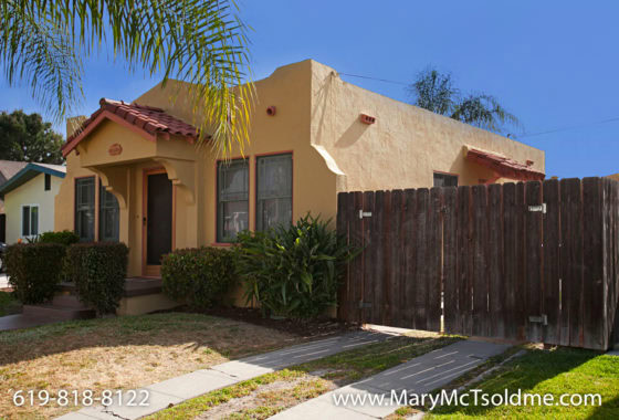 Spanish-style bungalow at 4433 Bancroft Street in Normal Heights featuring a yellow stucco exterior, terracotta roof tiles, and a wooden privacy fence.