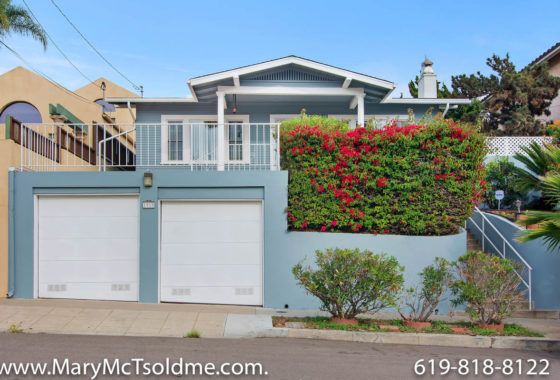 Blue Craftsman-style home with a two-car garage, white trim, and vibrant red bougainvillea at 1919 29th Street.